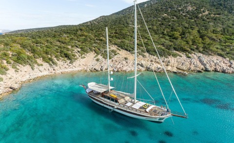 Turquoise sea with a yacht anchored near rocky coastline
