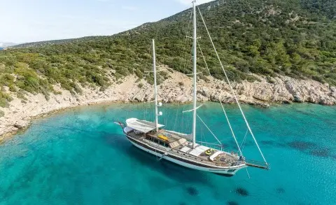 Turquoise sea with a yacht anchored near rocky coastline