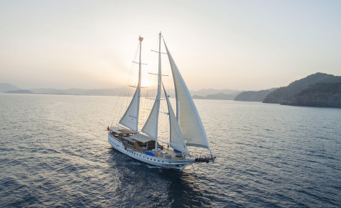 Sailing yacht with multiple masts on open sea at sunset