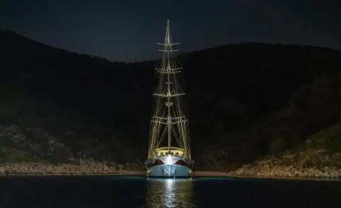 Yacht Tersane 8 lit up at night in a calm harbor with hills in background