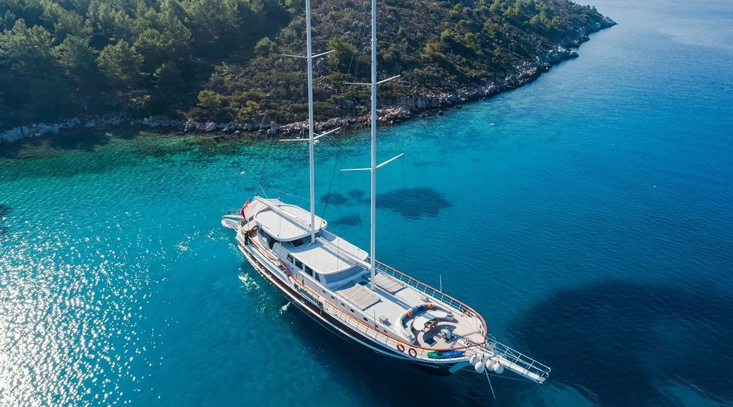 Vista Mare yacht anchored in clear blue water near rocky coastline at sunset