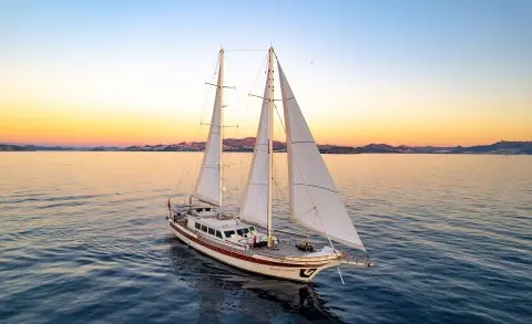 Double Eagle luxury yacht sailboat on calm sunset water with sails raised