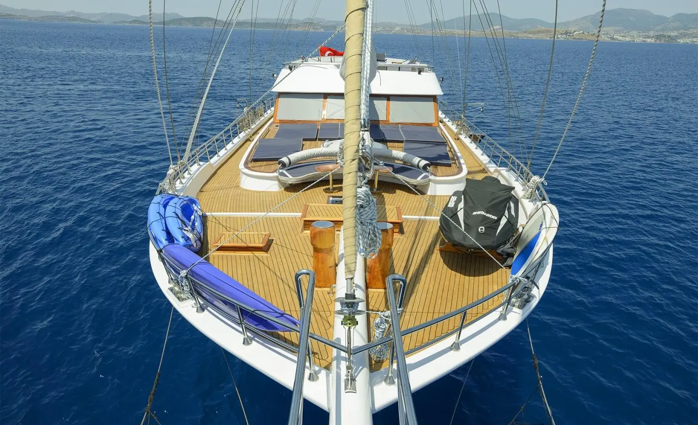 View of the yacht Bella Mare from the bow with sunken deck seating and blue sea