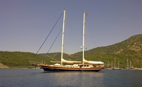 Kaya Guneri 4 classic sailing yacht anchored in calm blue harbor with hills behind