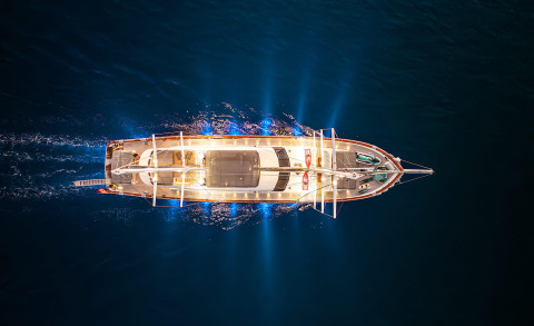 Overhead view of a lit gulet yacht cruising at night on the sea