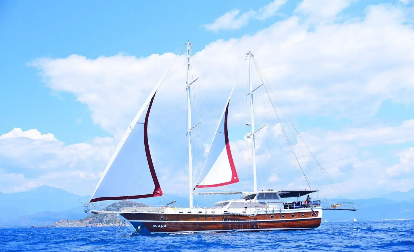 Maya yacht with white sails on blue sea at sunset, calm waters