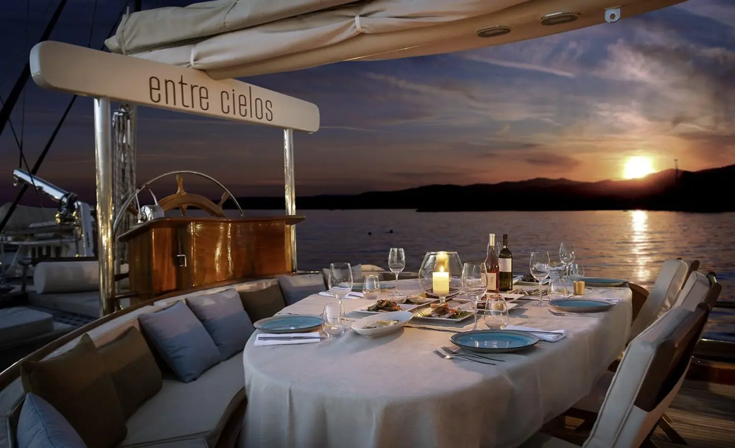 Evening yacht dining aboard Entre Cielos under sunset sky, table set