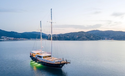 Happy Days luxury yacht anchored in calm water with shoreline hills in the distance