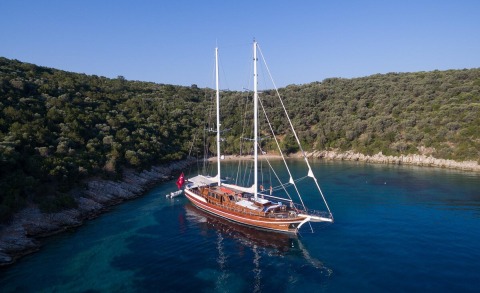 Grace 1 wooden-hulled sailing yacht anchored in clear blue water near rocky coastline