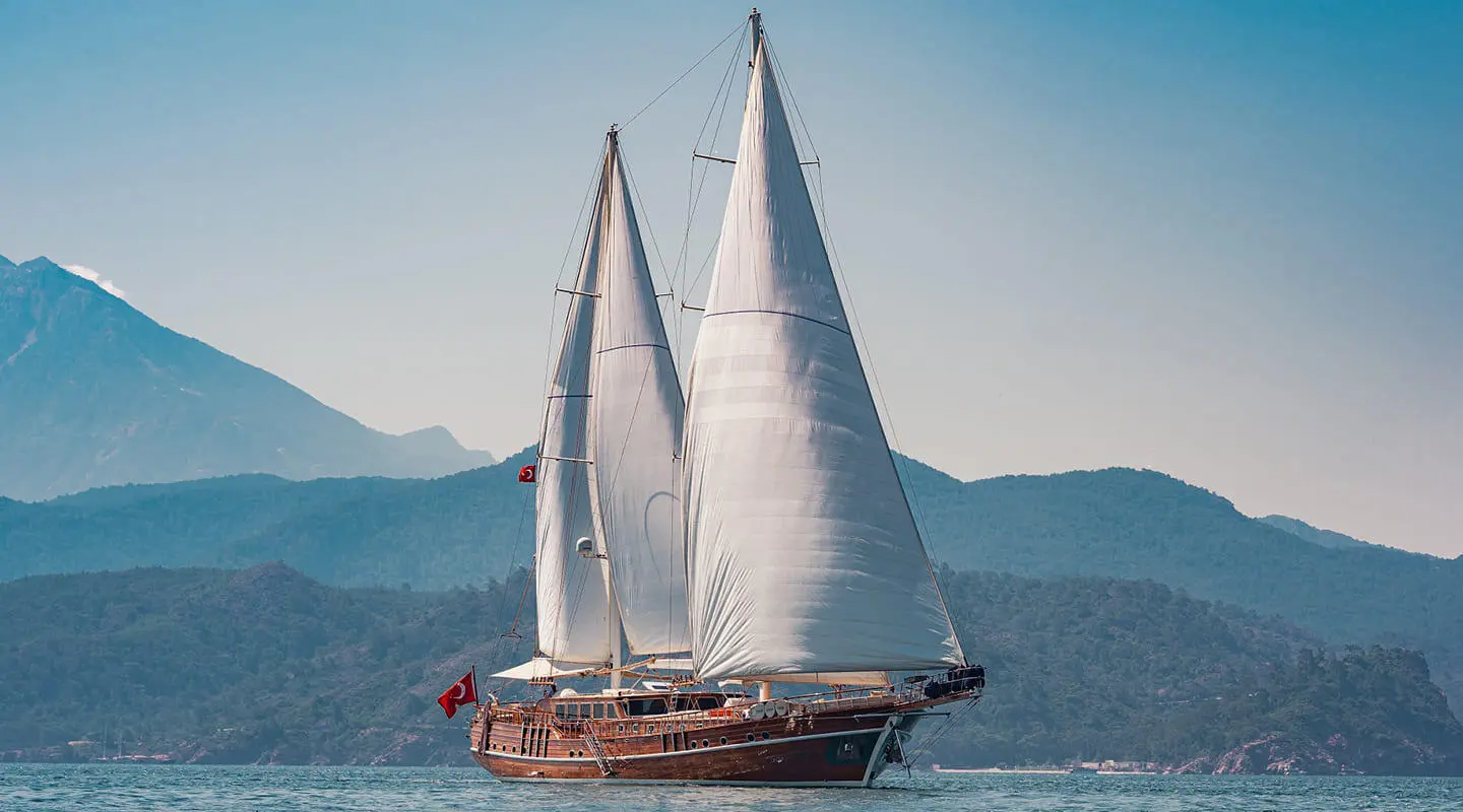 Luxurious yacht Lycian Queen sailing with full sails at sunset over calm blue sea