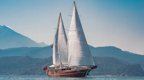 Luxurious yacht Lycian Queen sailing with full sails at sunset over calm blue sea