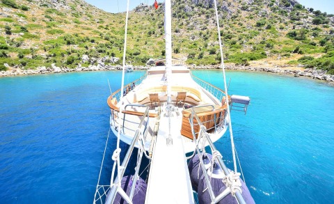 Luxurious yacht deck seen from bow with seating and rigging amid bright blue water
