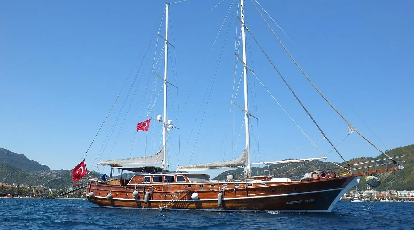 Sailing yacht Kaptan Mehmet Bugra anchored, wooden deck, sails furled by calm blue water