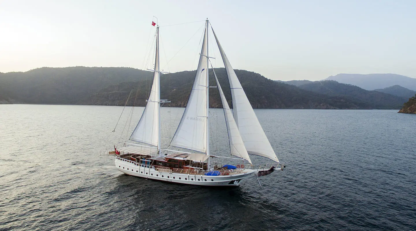 Kayhan 5 luxury gulet sailing on calm blue waters at sunset with sails raised