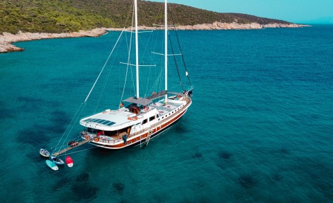 Gulet Bodrum Queen anchored in clear blue water near rocky shoreline