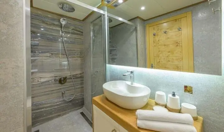 Master cabin with king bed, white bedding, wood cabinetry, and ensuite