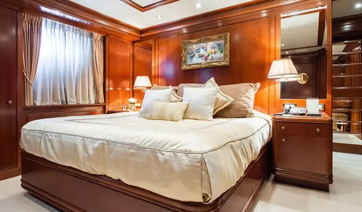 Master cabin with king bed, beige bedding, wood walls, and ensuite access
