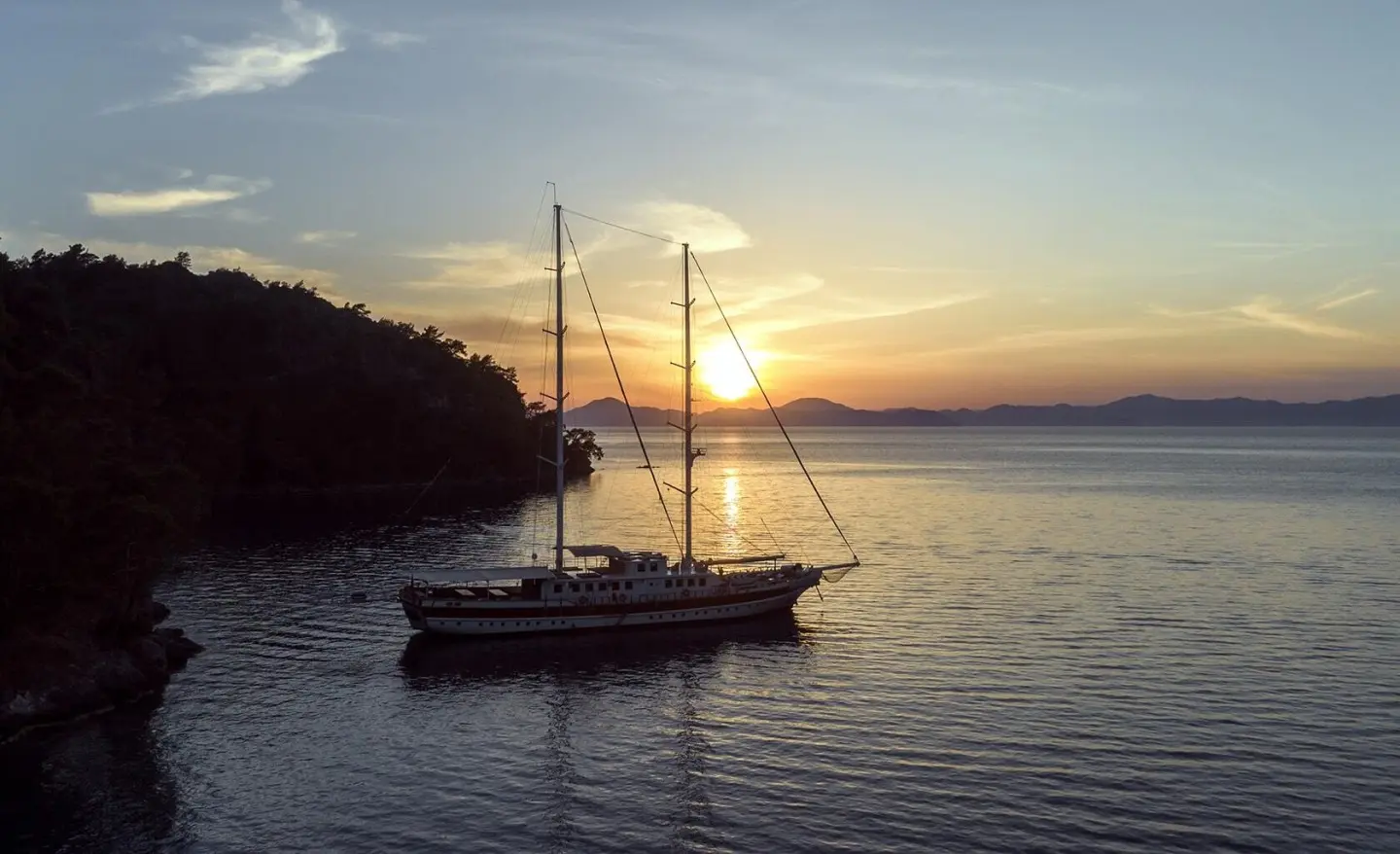 Sunset over calm sea with a luxury gulet yacht anchored in the water