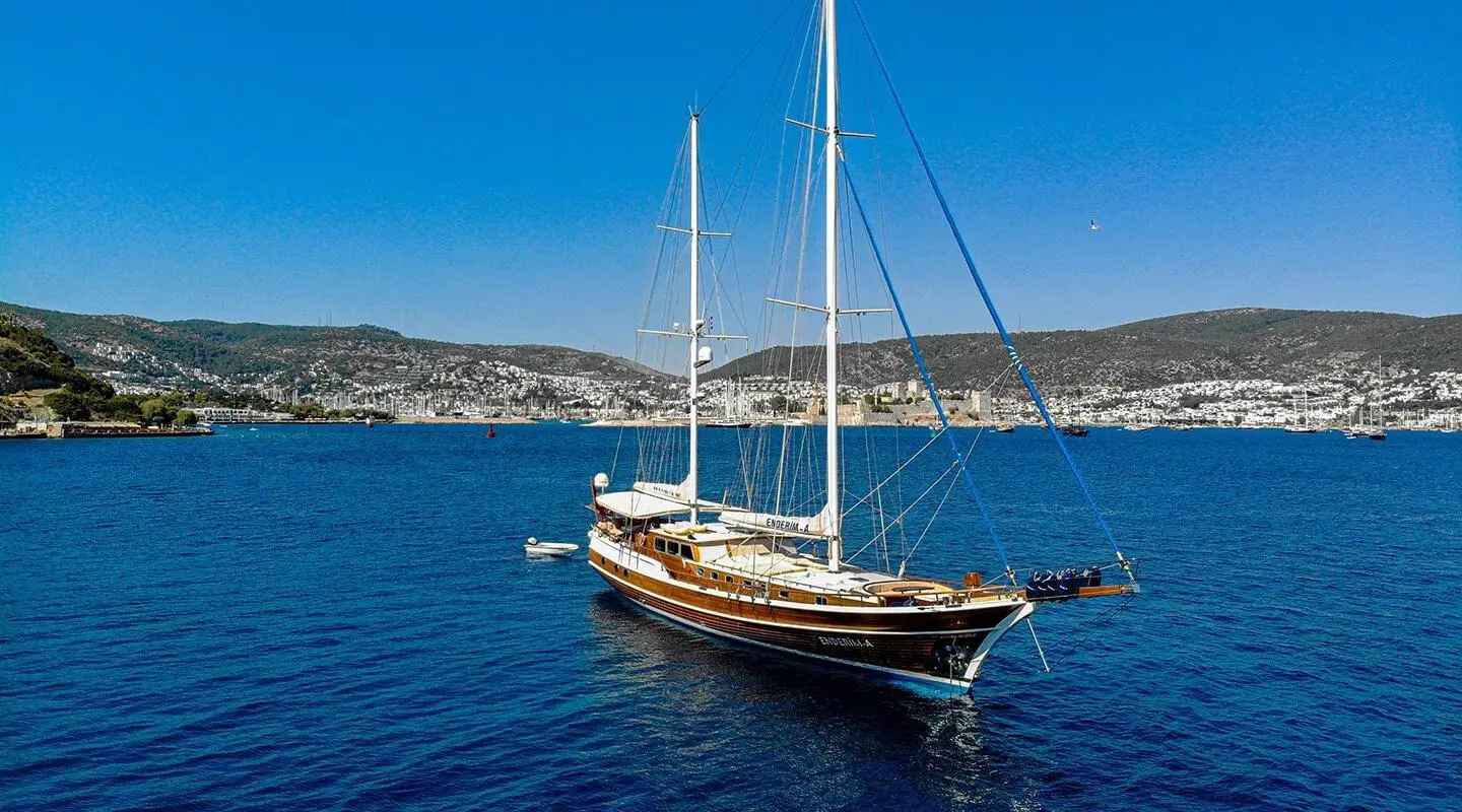 Gulet Enderim A anchored in calm blue sea with hills in background
