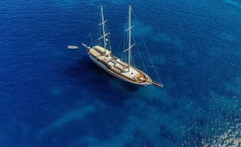 Enderim A yacht anchored in clear blue sea under sunset sky