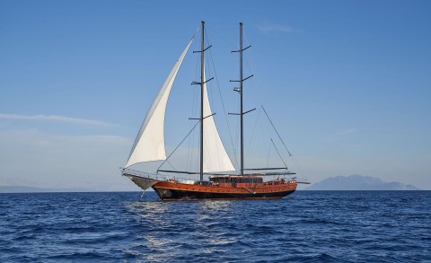 Luxurious sailing yacht Stella Maris at sea with two masts, wooden red hull, white sails unfurled