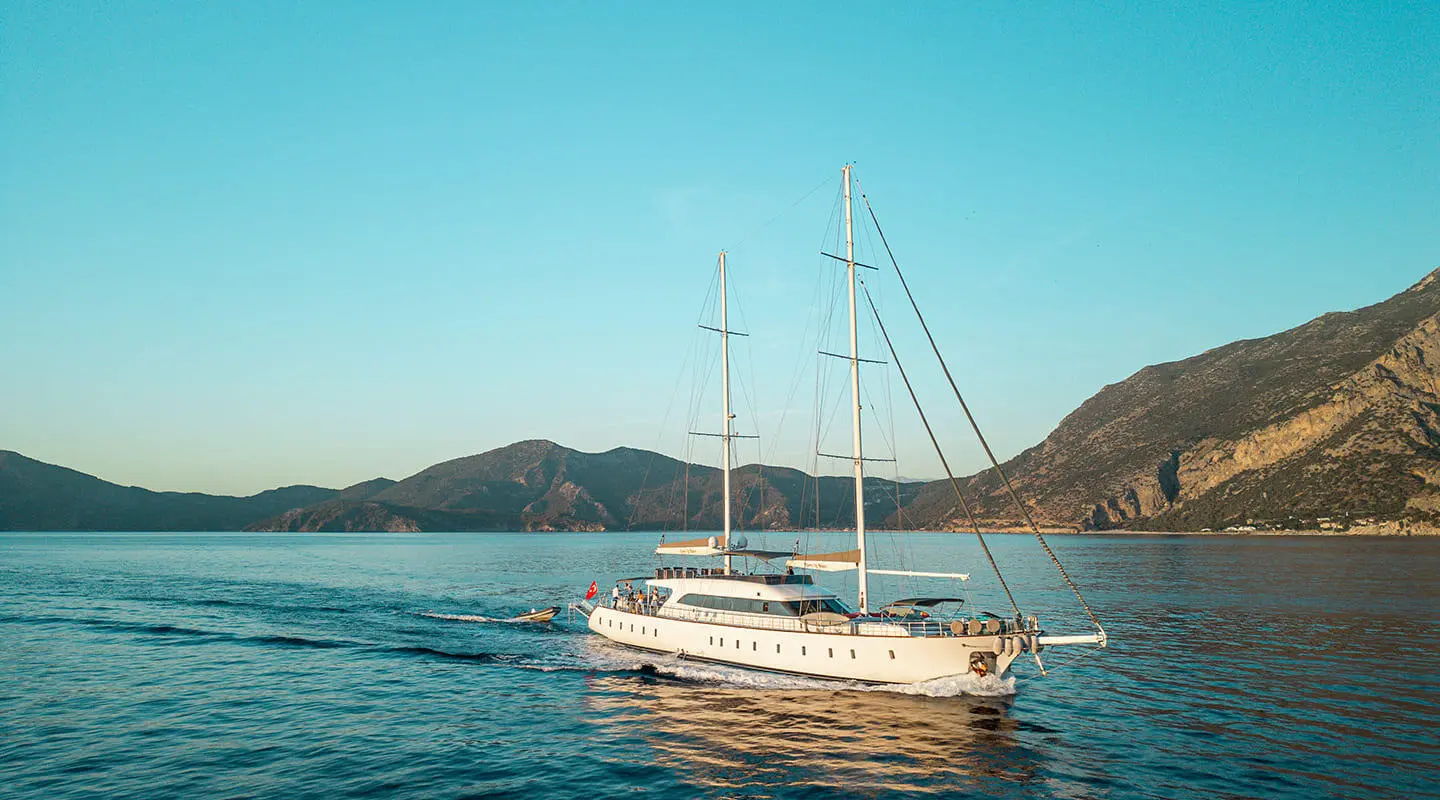Gulet yacht Queen Of Makri anchored calm blue sea with hills in background