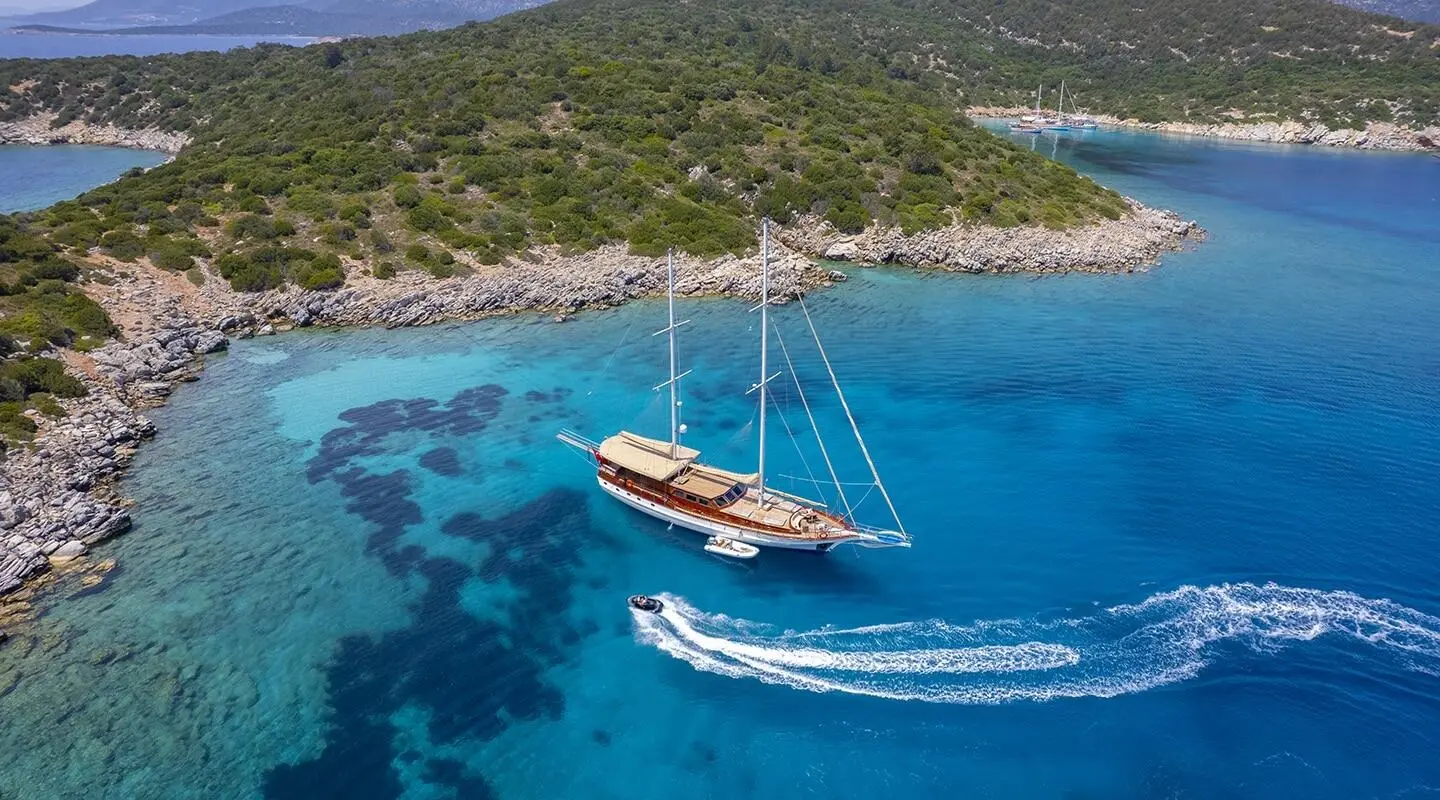 Arabella yacht anchored near a rocky coastline with clear blue water