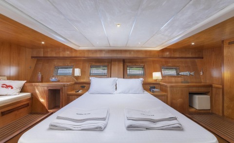 Queen Of Sea luxury yacht cabin with wooden panels, queen bed, white linens, and matching bedside tables
