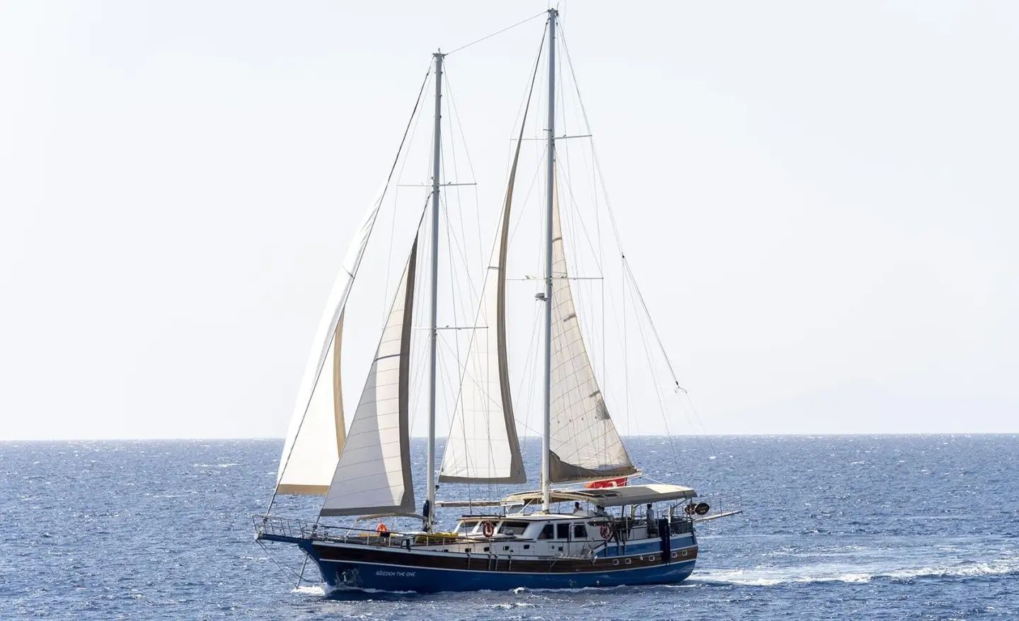 Gozdem The One yacht sailing with tall masts on calm blue sea at sunset