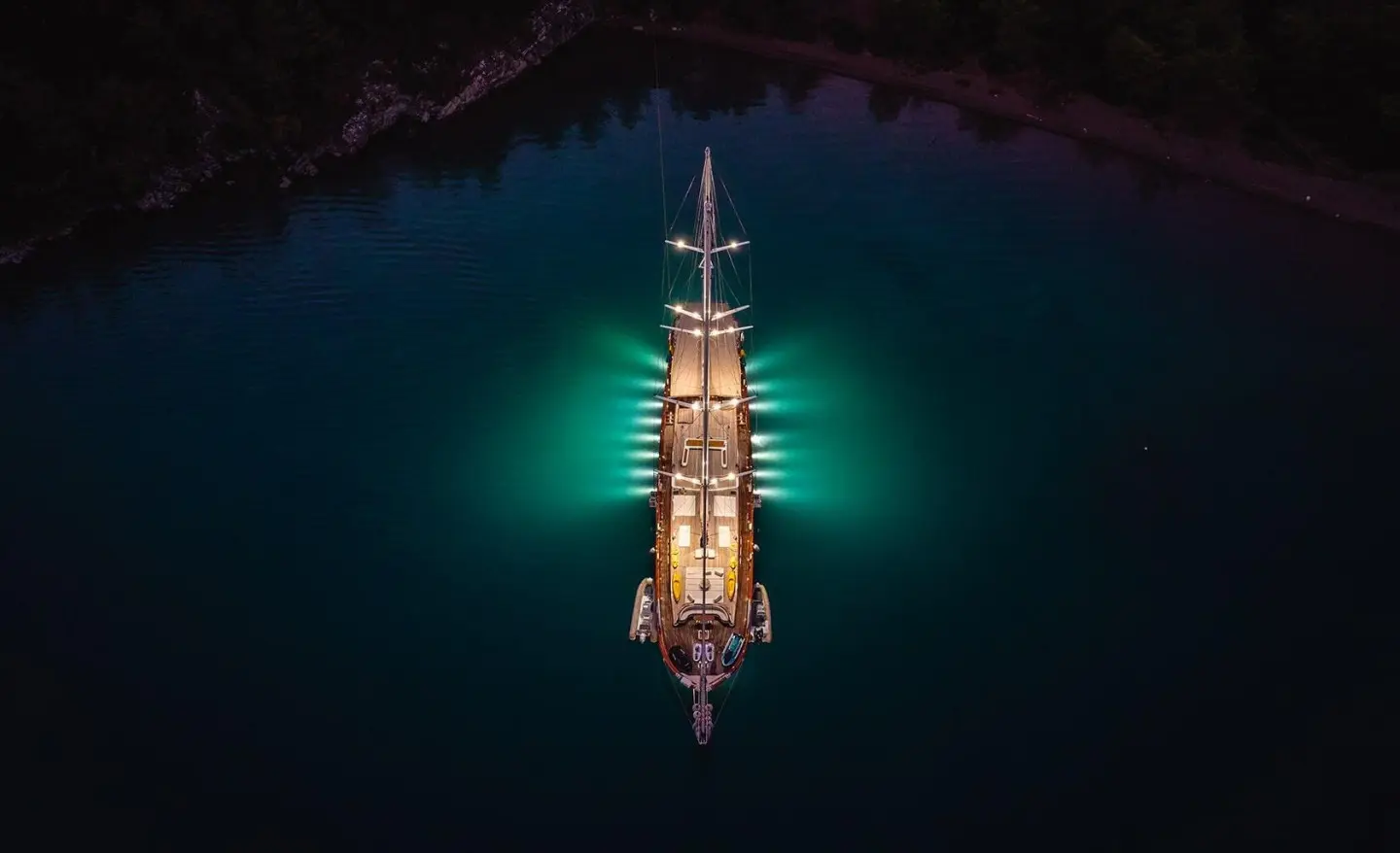 Yacht La Bella Vita seen from above at dusk, illuminated deck glow on calm sea