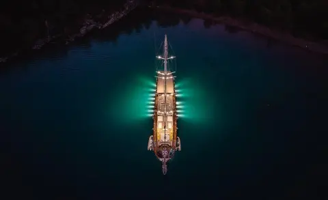 Yacht La Bella Vita seen from above at dusk, illuminated deck glow on calm sea