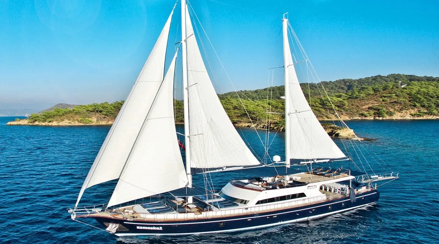 Maske 2 luxury sailing yacht with white sails on blue sea near green coastline