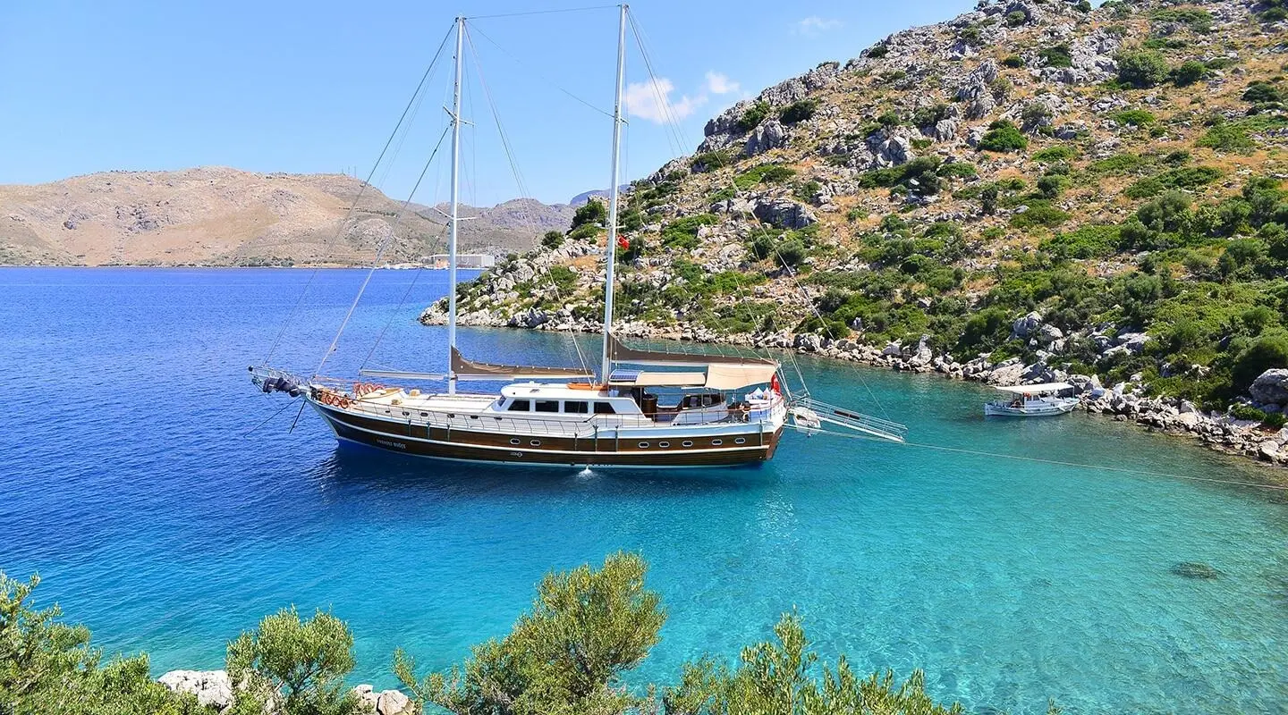 Gulet Prenses Bugce anchored in turquoise bay with rocky coast and clear water