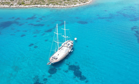 White luxury sailing yacht Prenses Esila anchored in clear blue sea by the shore