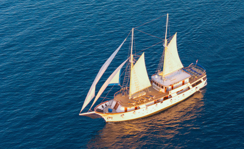 Mendula yacht seen from above with sails raised, white hull and wooden deck
