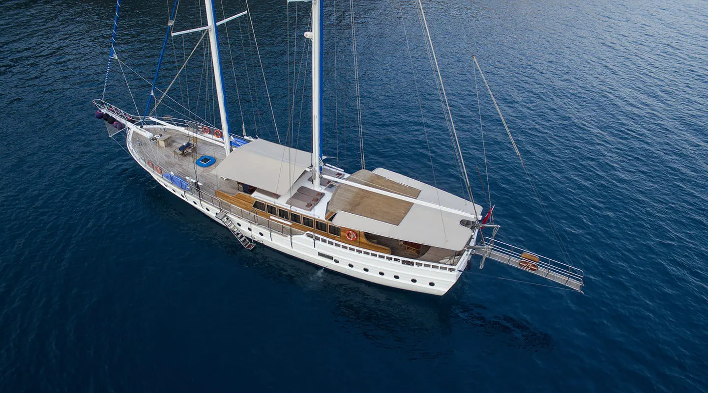 A gulet yacht Kayhan 8 anchored in calm blue sea, seen from above.
