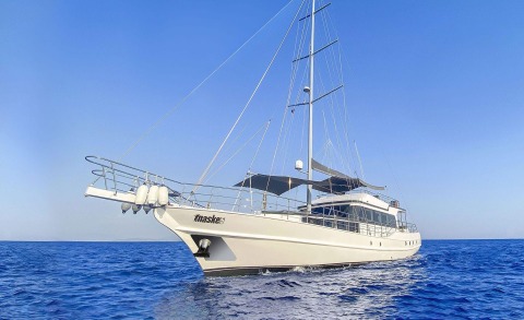 Maske5 yacht sails on blue sea with grooming gulet, deck rails and shade canopy visible
