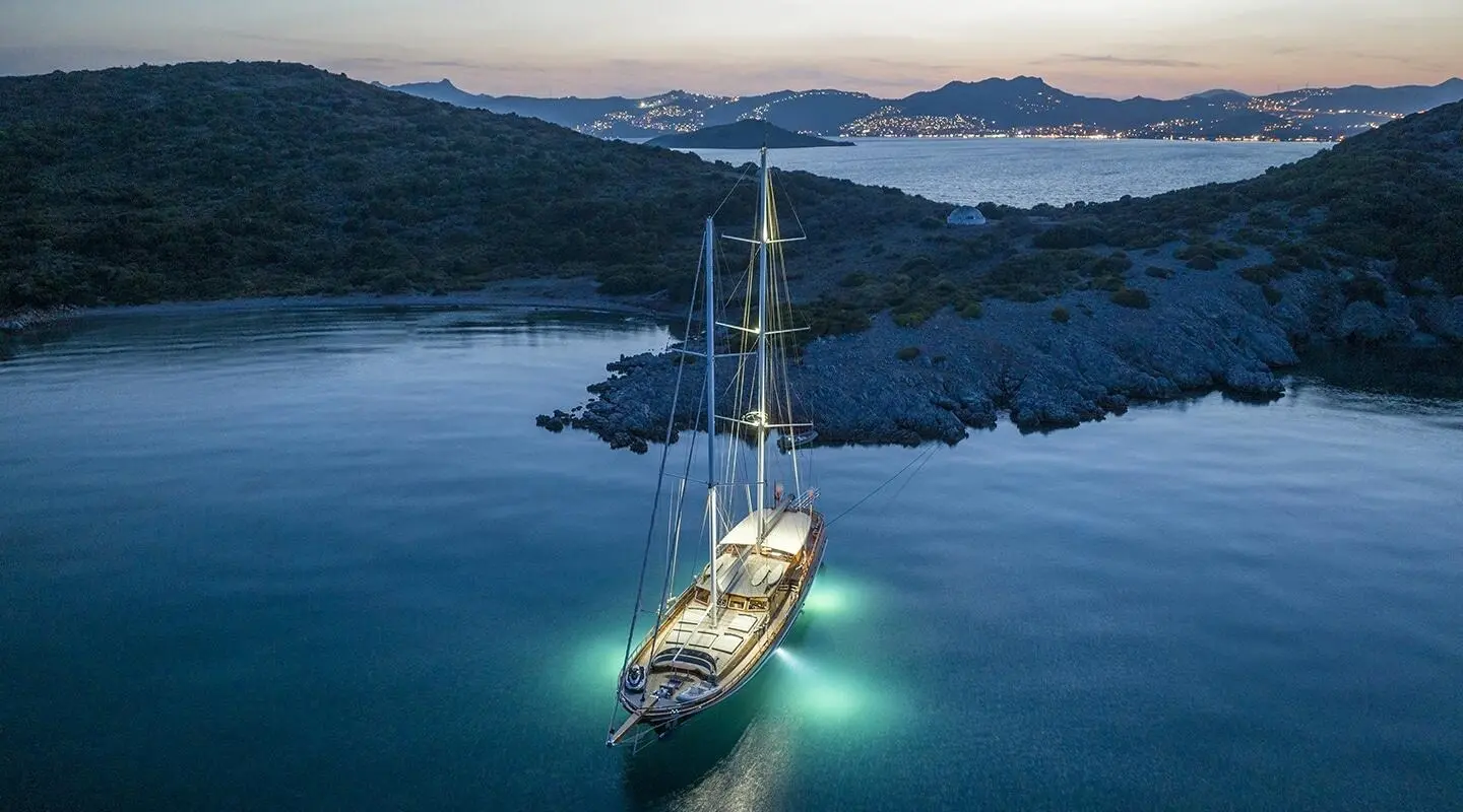 Yacht Bedia Sultan anchored at sunset, sleek hull reflecting on calm blue water