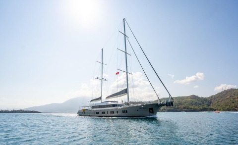 Two-masted yacht De Love gliding on calm water under a bright sunny sky