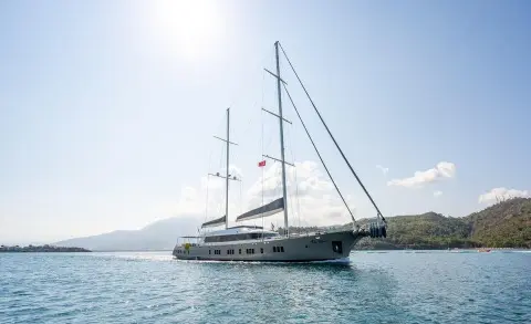 Sailing motor yacht De Love anchored near a pier with clear blue water