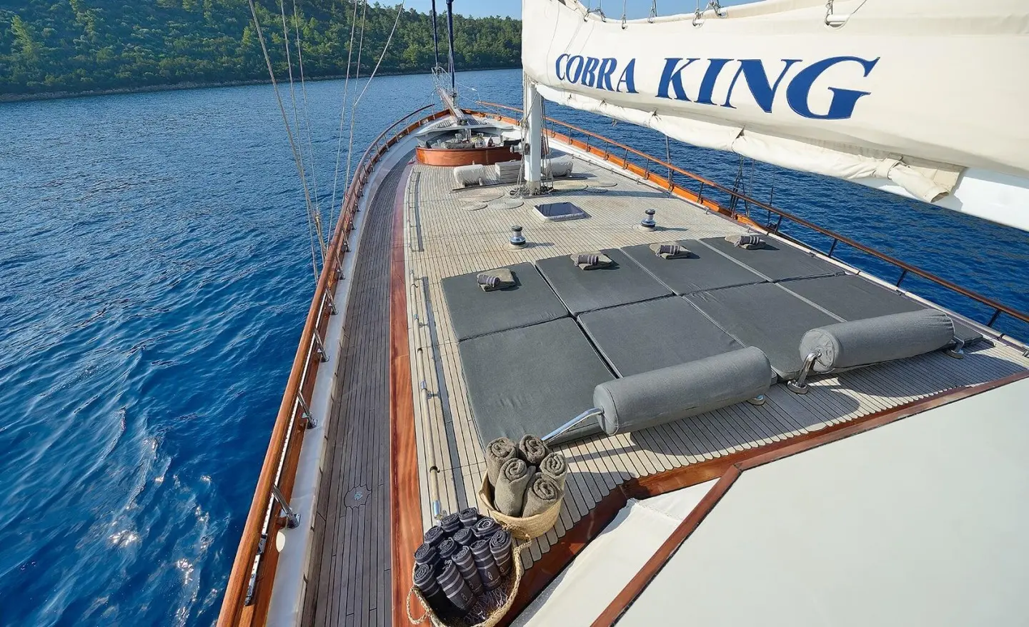 View along the Cobra King yacht deck at sunset with wooden railing and hatch