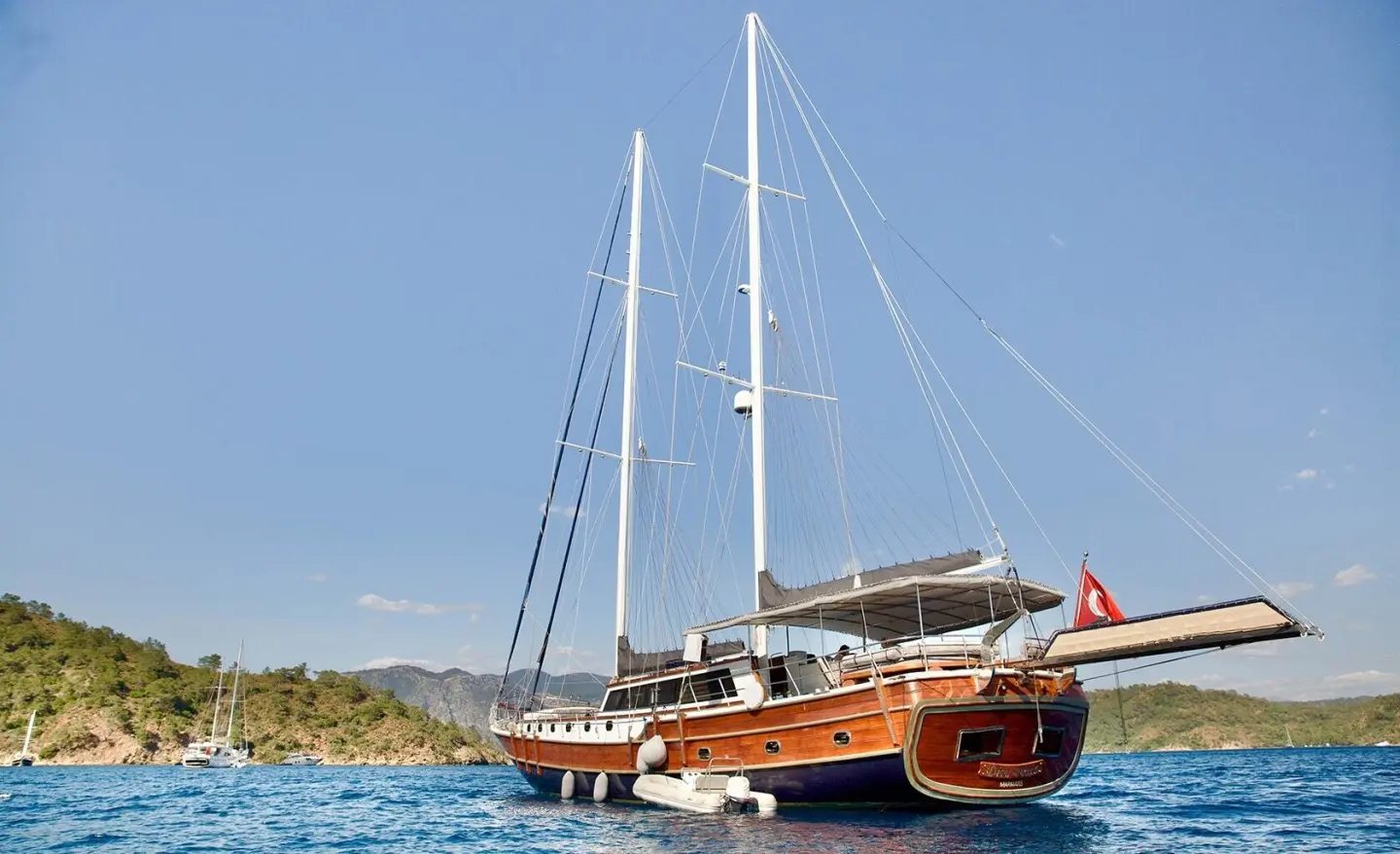 Diva Deniz luxury gulet at anchor, sails down, wooden hull gleaming by calm blue water