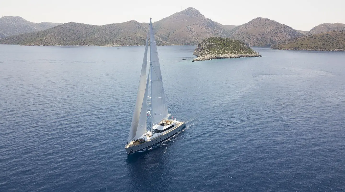 All About U 2 sailing near rocky islands in calm blue sea