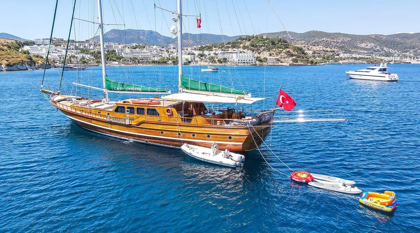 Lady Christa luxury gulet with wooden deck anchored in blue calm sea at sunset