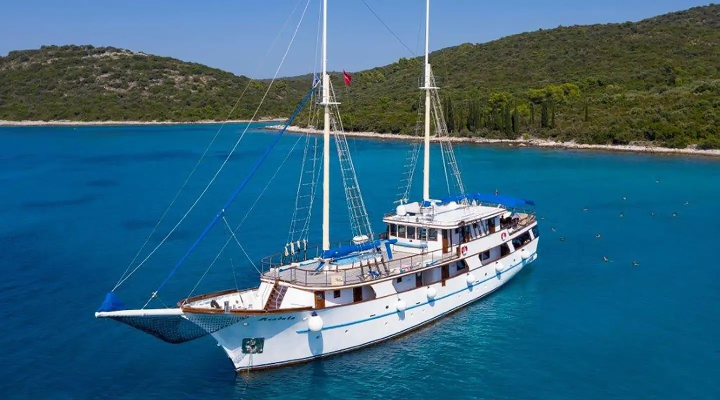 Mendula luxury gulet anchored in clear blue sea with hillside behind