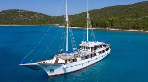 Mendula luxury gulet anchored in clear blue sea with hillside behind