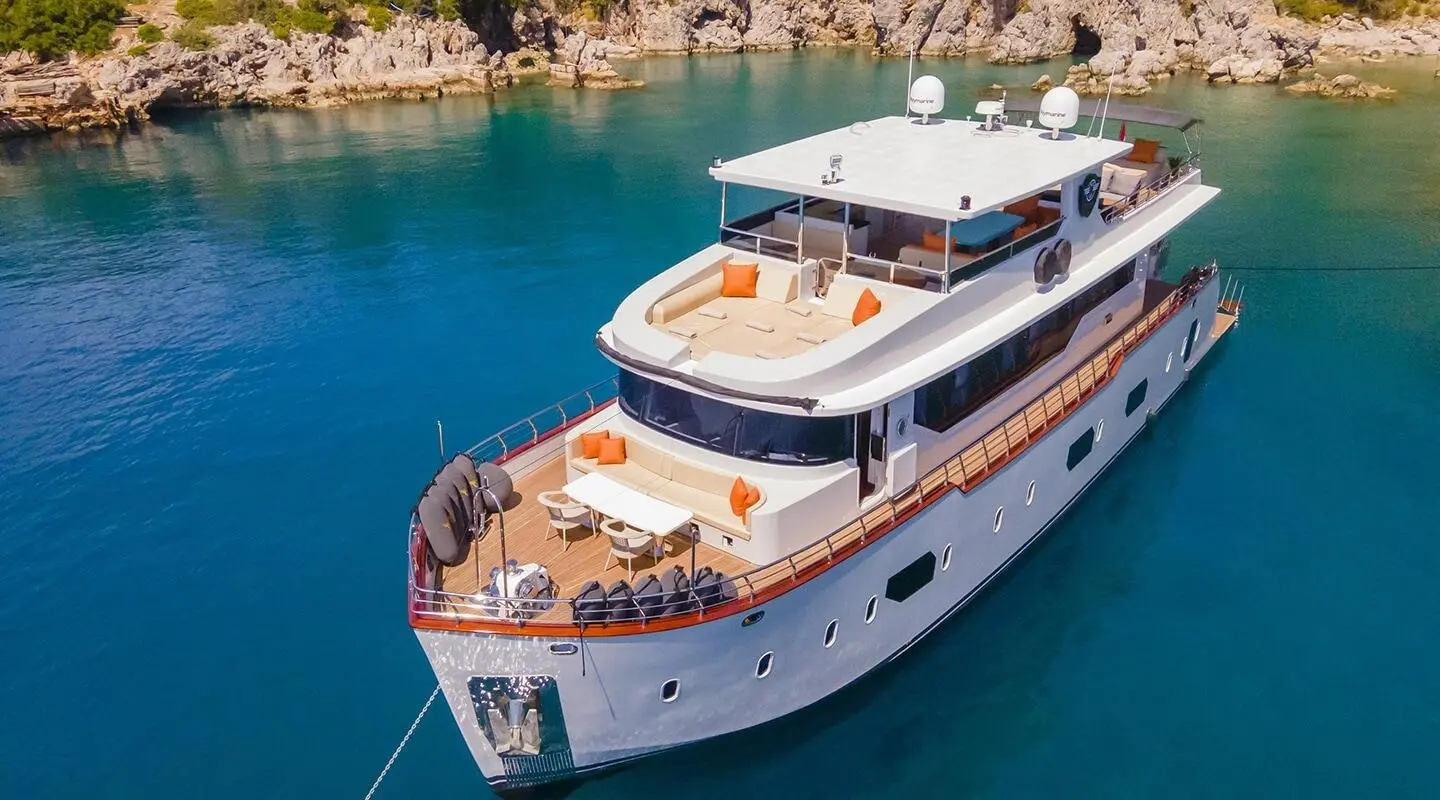 A luxury motor yacht named Simay M anchored near a sandy coastline with clear blue water
