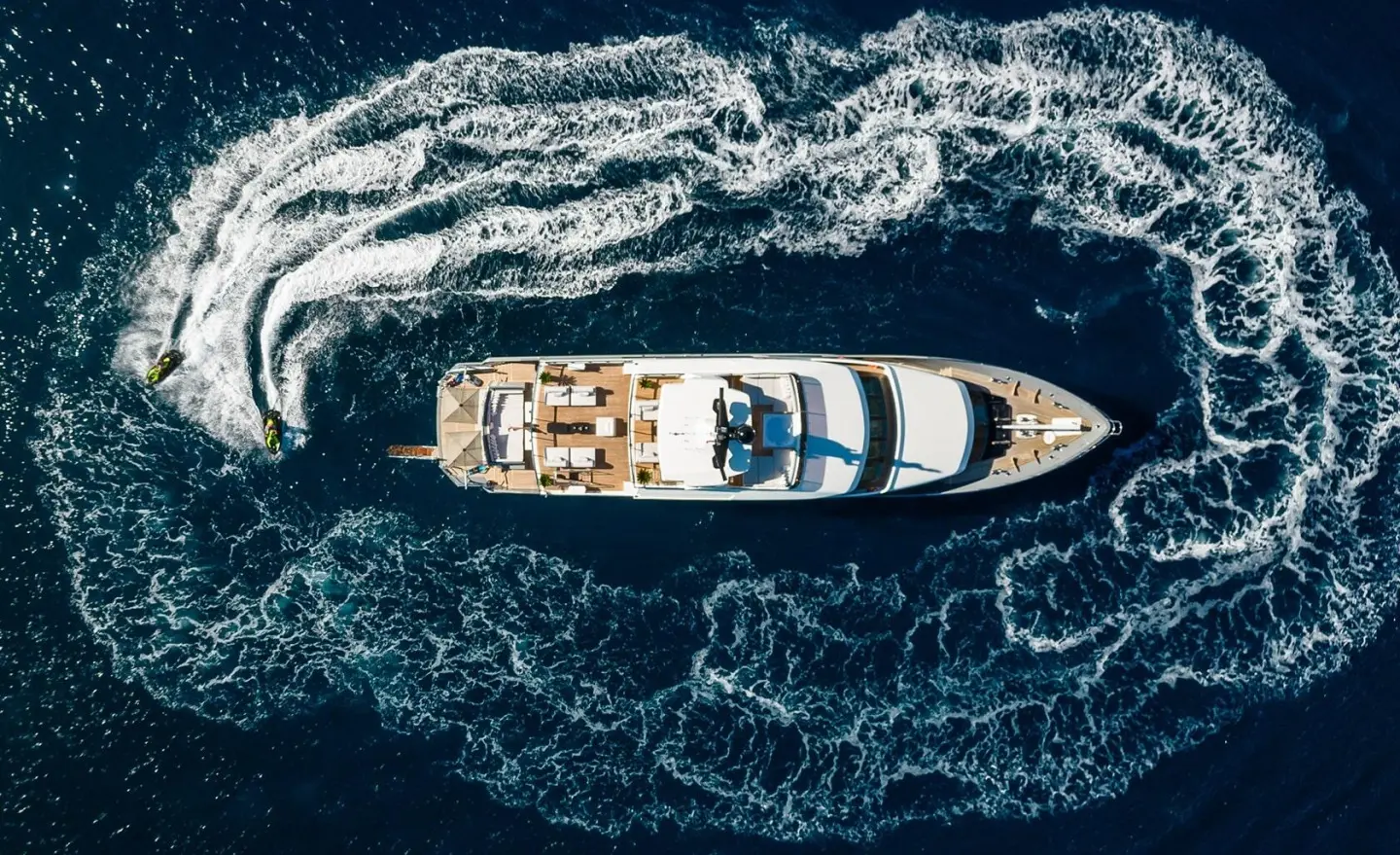 A luxury motor yacht Illusion II floats in dark blue sea from overhead view