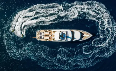 A luxury motor yacht Illusion II floats in dark blue sea from overhead view