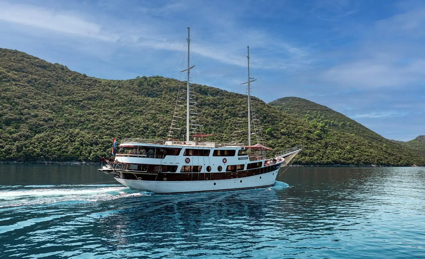 Cesarica luxury gulet sailing near green hills on calm turquoise water